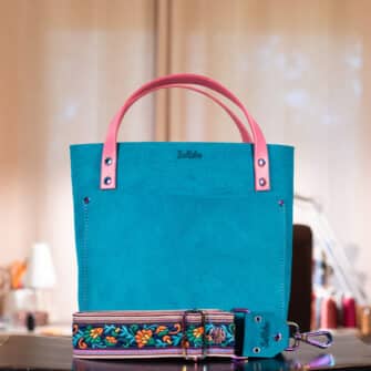 Alicia - Round 1 - SoRetro Verdura Mini+ FYG Leather Crossbody Tote – La Tela Acqua with Limited Flores del Campo on Serape SortaWide Stripes Webbing – Chromalusion Hardware